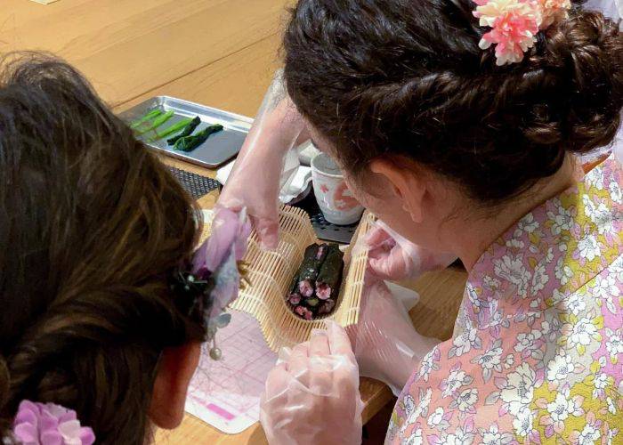 Two girls wearing kimono making sushi in a Kyoto cooking class.